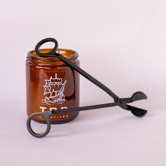 Brown glass jar with black tongs on a white background